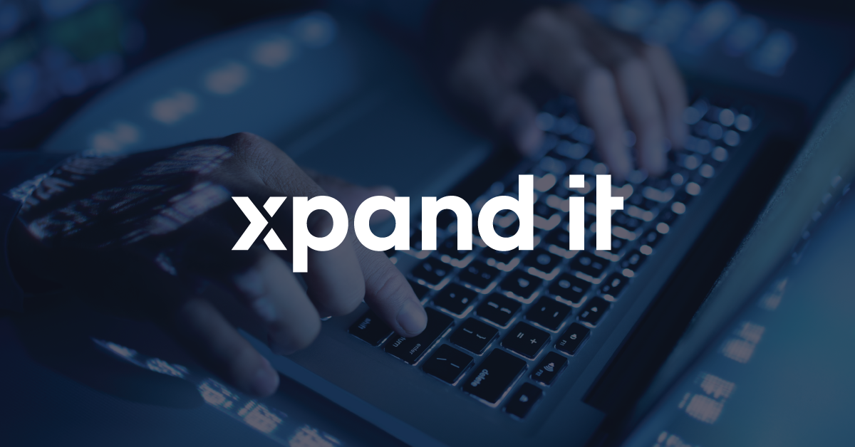 Imagem de um teclado retroiluminado com mãos a digitar, projetando reflexos digitais em azul. A versão da imagem com logótipo apresenta "Xpand IT" em destaque no centro, reforçando a identidade da marca.