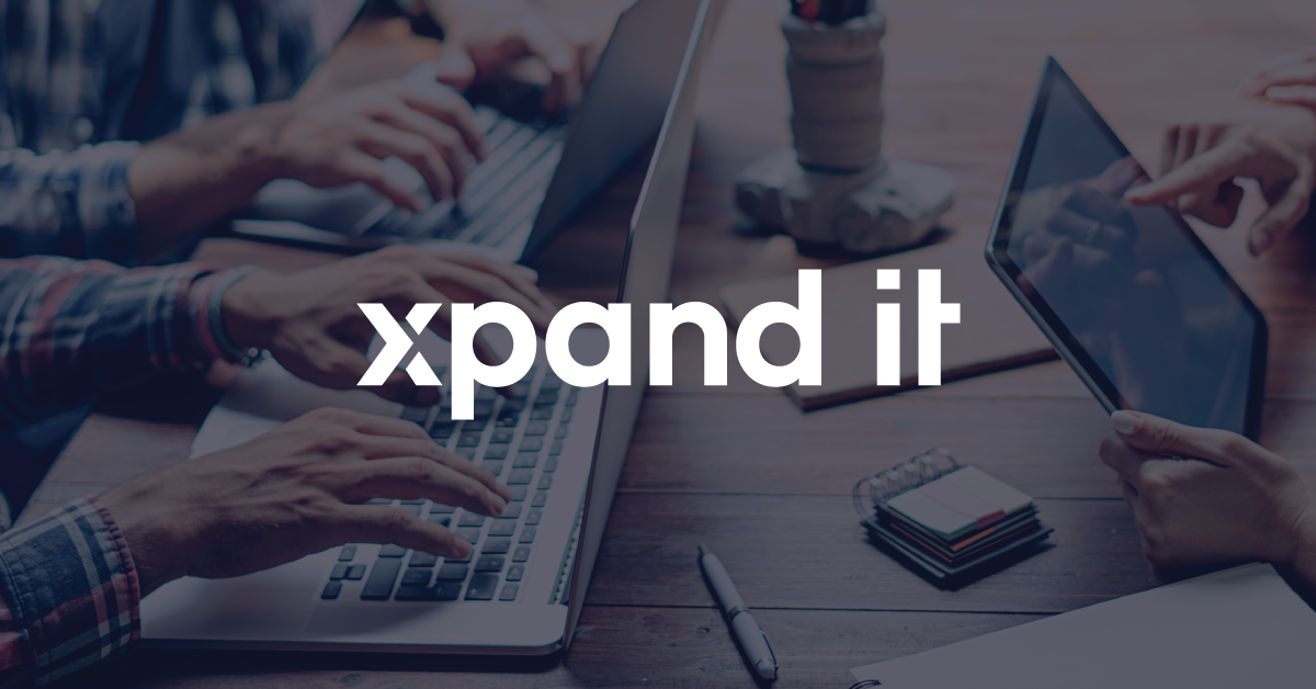 Hands typing on laptops and interacting with a tablet, with the "Xpand IT" logo overlaid, symbolizing innovation and technology.