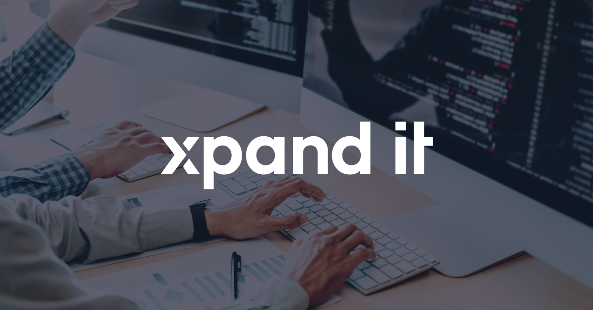 Two people programming on computers with code visible on the screens, representing software development and system integration. "Xpand IT" logo prominently displayed.