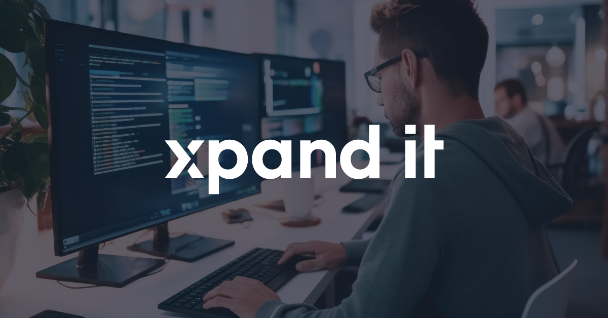 Tech professional working at a modern desk with multiple monitors displaying code. The image features an overlaid Xpand IT logo at the center.