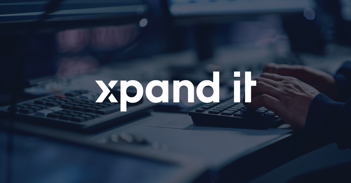 Hands typing on a keyboard in a modern tech environment, symbolizing data analytics, consulting, and digital innovation. "Xpand IT" logo prominently displayed.