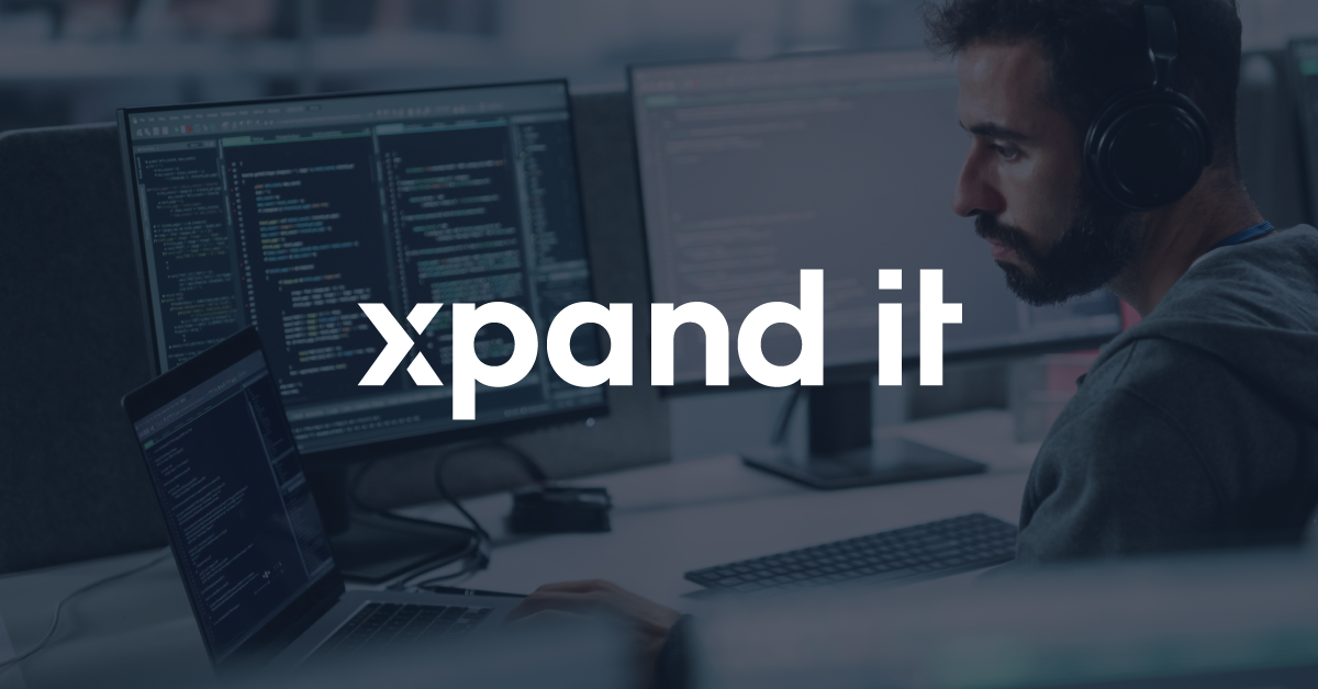 Pessoa a programar num portátil, com código exibido no ecrã, representando inovação e desenvolvimento de software. O logótipo "Xpand IT" está sobreposto na imagem.