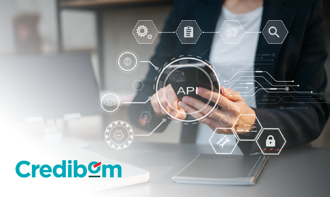 Profissional a utilizar um smartphone com ilustrações digitais de ícones tecnológicos e a palavra “API”, simbolizando integração digital, inovação e automação no setor financeiro. O logótipo da Credibom destaca a identidade da marca.