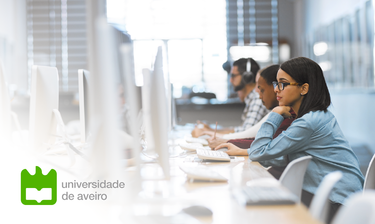 Estudantes a trabalhar em computadores numa sala de informática moderna e bem iluminada, com o logótipo da Universidade de Aveiro visível. A imagem transmite inovação tecnológica e excelência académica no contexto do ensino superior.