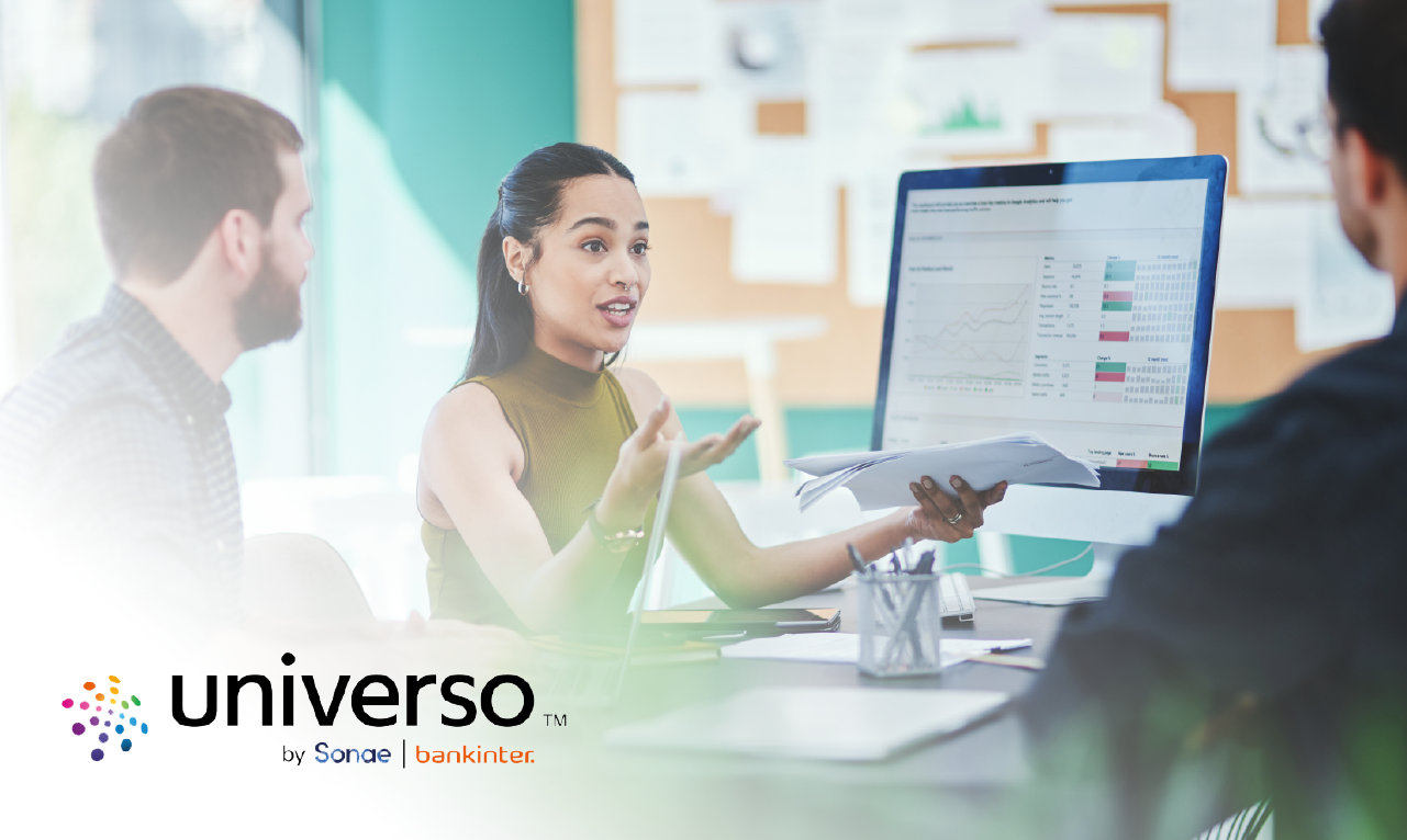 Três pessoas numa reunião de trabalho, com destaque para uma mulher a apresentar dados num ecrã com gráficos e tabelas. O logótipo "universo by Sonae | bankinter" aparece no canto inferior esquerdo.