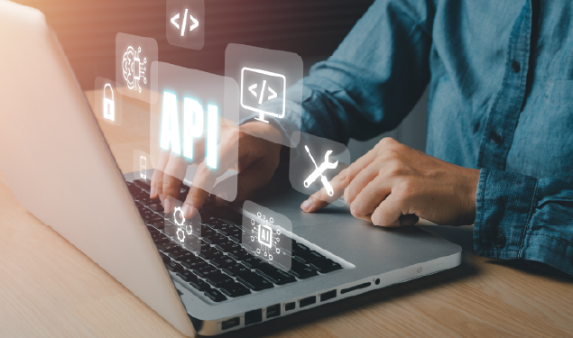 Person typing on a laptop with floating digital icons related to API development and integration, highlighting the term "API", representing technology and business automation.