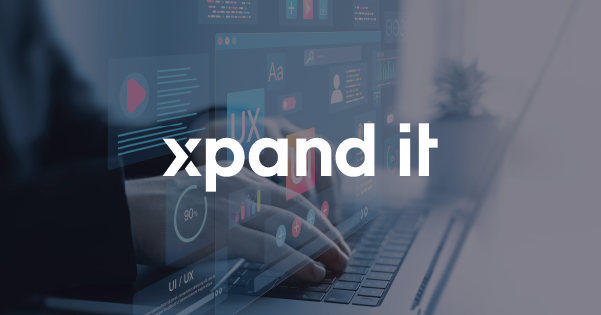Ecrã com interfaces digitais flutuantes de UX e UI, sobreposição de gráficos e elementos visuais, com mãos a escrever num portátil ao fundo. Logótipo da Xpand IT em destaque no centro.