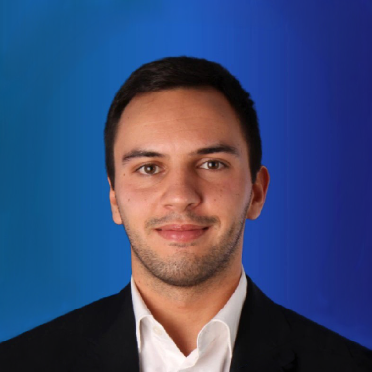 Retrato de Francisco Roig, com blazer escuro e camisa branca, sobre um fundo azul.